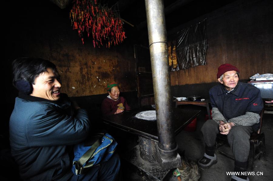 Postman Zhang Meichong (L) talks to an old couple on his way to send letters at a mountainous village in Enshi, central China's Hubei Province, Dec. 23, 2012. Equipped with a stick and two bags, Zhang Meichong, a village postman, has been working in the mountainous area for 15 years and traveled a distance about 180,000 kilometers these years. (Xinhua/Hao Tongqian)  