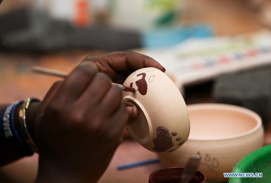 A woman paints on a ceramic bowl at the Kazuri factory in Nairobi, Kenya, Jan. 8, 2013. Kazuri, which means "small and beautiful" in Swahili, began in 1975 as a workshop experimenting on making handmade beads. The factory employs over 340 women, mostly single mothers. Its handmade and hand-painted ceramic jewellery and pottery products have been exported to over 30 countries and regions worldwide. (Xinhua/Meng Chenguang)