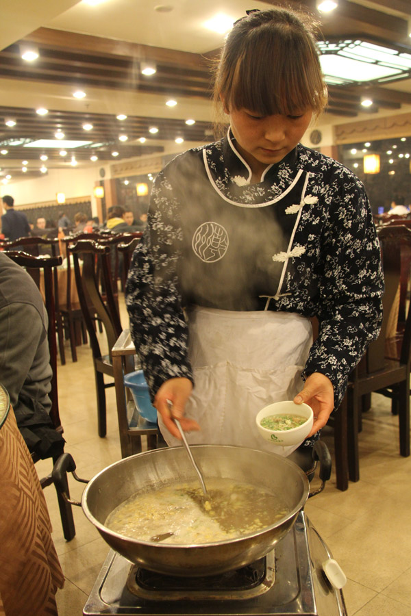 A waitress cooks "Hanshuimian", noodle in simmered meat soup, beside the table in a restaurant in Xi'an, capital of Northwestern China's Shaanxi Province on January 9, 2013. (CRIENGLISH.com/Liu Kun) 