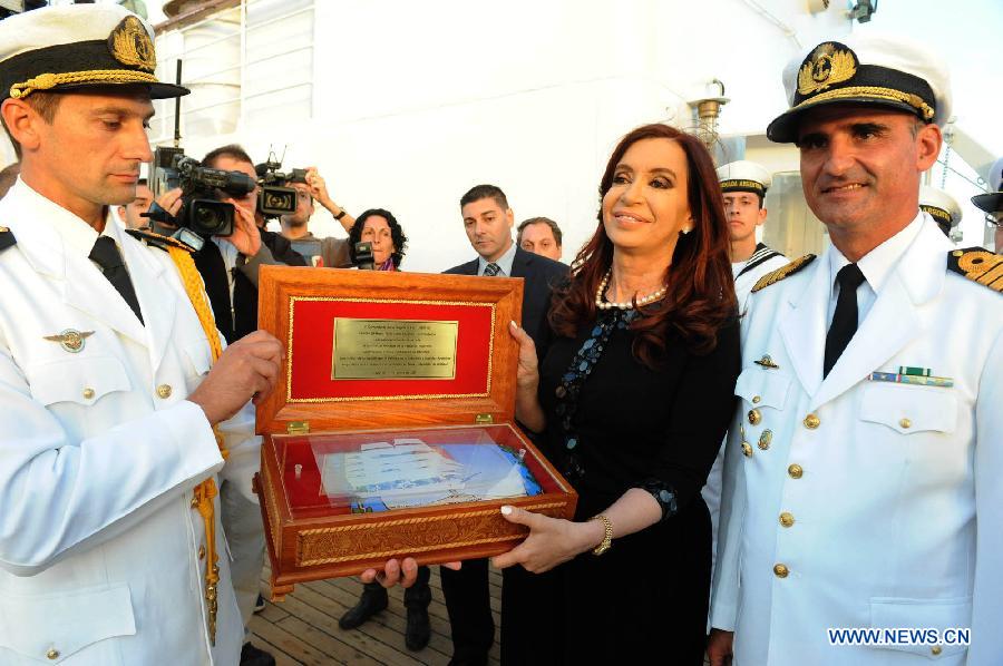 Argentina's President Cristina Fernandez (2nd R) receives a gift from Frigate Libertad captain Pablo Lucio Saloni (1st R) in the port of Mar del Plata, Argentina, Jan. 9, 2013. The Frigate Libertad, which was held in Ghana from Oct. 2 to Dec, 19, 2012 due to a court order, arrived in Mar del Plata on Wednesday, according to local press. (Xinhua/TELAM)