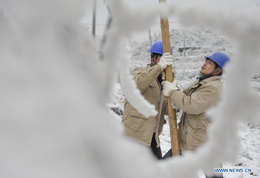 Workers clean ice on the power line with a bamboo stick in Yongsha Village of Shuangliu Township in Kaiyang County, southwest China's Guiyang, Jan. 10, 2013. Local power grid company sent workers to clean power lines which couldn't melt the ice with automatic equipment. (Xinhua/Ou Dongqu) 