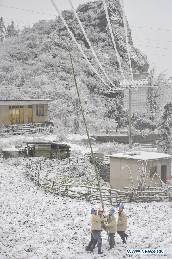 Workers clean ice on the power line with a bamboo stick in Yongsha Village of Shuangliu Township in Kaiyang County, southwest China's Guiyang, Jan. 10, 2013. Local power grid company sent workers to clean power lines which couldn't melt the ice with automatic equipment. (Xinhua/Ou Dongqu)