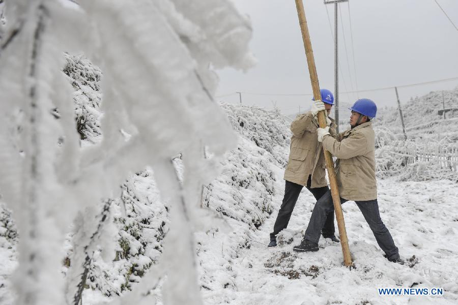 Workers clean ice on the power line with a bamboo stick in Yongsha Village of Shuangliu Township in Kaiyang County, southwest China's Guiyang, Jan. 10, 2013. Local power grid company sent workers to clean power lines which couldn't melt the ice with automatic equipment. (Xinhua/Ou Dongqu)