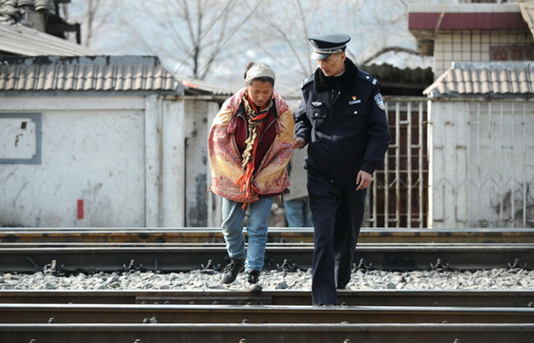 Zhu Dong helps a woman of the Yi ethnic group cross a railway line in Yuexi county, Southwest China's Sichuan province, on Jan 8, 2013. (Photo/Xinhua)