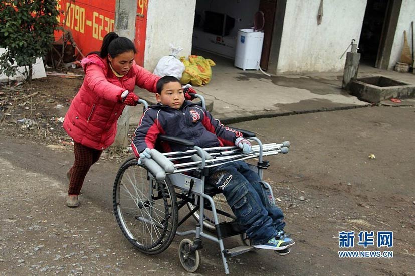 Wu Sulan pushes a wheelchair to send her son Kangle to school on Jan.9, 2013. The wheelchair was donated by Kangle’s classmates. (Xinhua/Huchao)