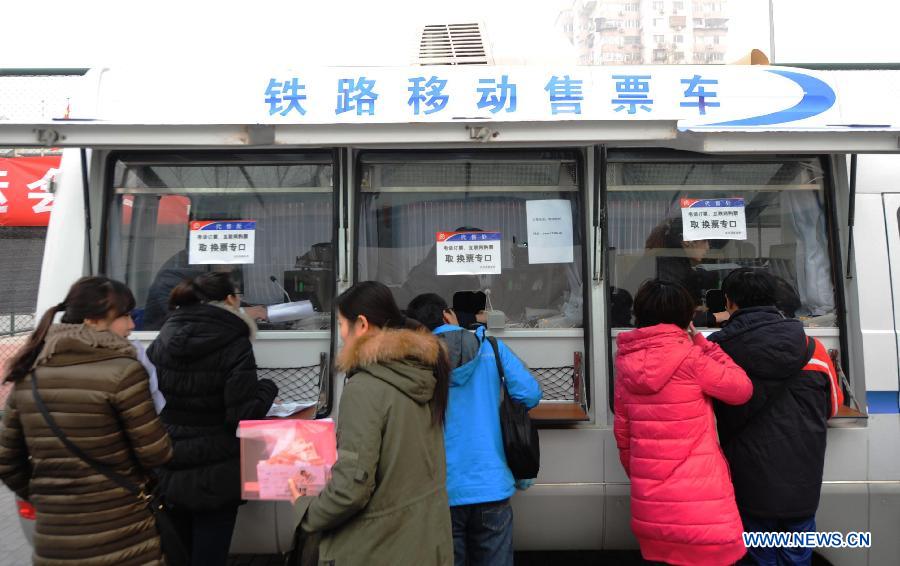 People buy train tickets at a mobile ticket office in Beijing, capital of China, Jan. 11, 2013. Two vehicles were parked in the Chaoyang District on Friday to facilitate people's purchase of train tickets. (Xinhua/Li Wen)