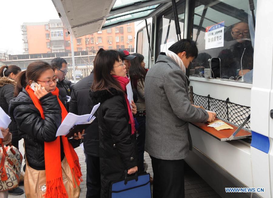People buy train tickets at a mobile ticket office in Beijing, capital of China, Jan. 11, 2013. Two vehicles were parked in the Chaoyang District on Friday to facilitate people's purchase of train tickets. (Xinhua/Li Wen)  