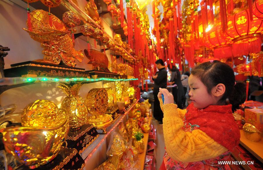 A child takes pictures of ornaments to greet the upcoming Spring Festival, which falls on Feb. 10 this year, at a shop in Haikou, south China's Hainan Province, Jan. 12, 2013. (Xinhua/Guo Cheng) 