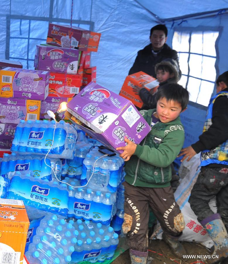 Children carry food and water for victims of a landslide disaster at Gaopo Village in Zhenxiong County, southwest China's Yunnan Province, Jan. 12, 2013. Landslide-affected villagers in Gaopo Village have been temporarily settled in tents and got life necessities. Forty-six people were killed in the Friday landslide. Another two people were injured. (Xinhua/Chen Haining) 