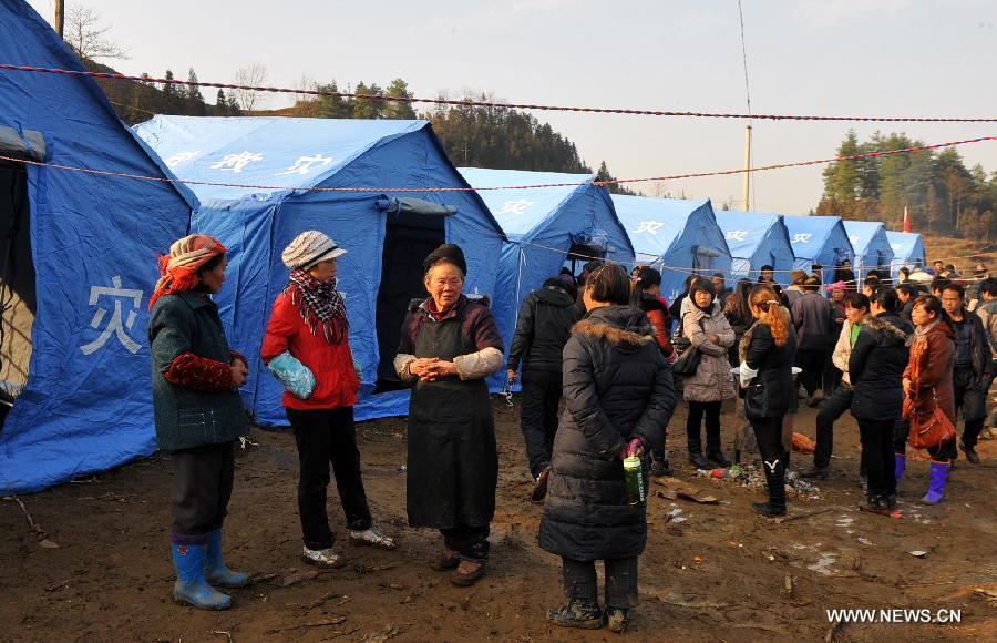 Landslide victims stand by temporary shelters rescuers installed for them at Gaopo Village in Zhenxiong County, southwest China's Yunnan Province, Jan. 12, 2013. Landslide-affected villagers in Gaopo Village have been temporarily settled in tents and got life necessities. Forty-six people were killed in the Friday landslide. Another two people were injured. (Xinhua/Chen Haining) 