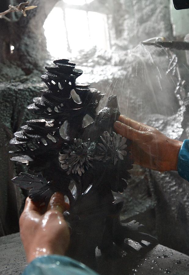 A craftsman named Hu Yongzhong washes a semi-finished handicraft made of chrysanthemum stone in a workshop in Enshi, central China's Hubei Province, Jan. 12, 2013.(Xinhua/Song Wen) 