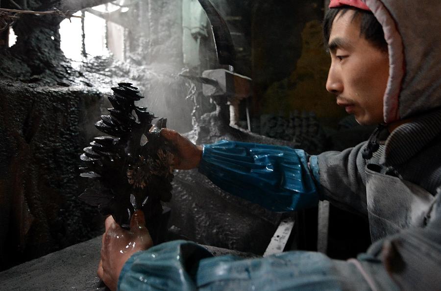 A craftsman named Hu Yongzhong washes a handicraft made of chrysanthemum stone in a workshop in Enshi, central China's Hubei Province, Jan. 12, 2013.(Xinhua/Song Wen) 