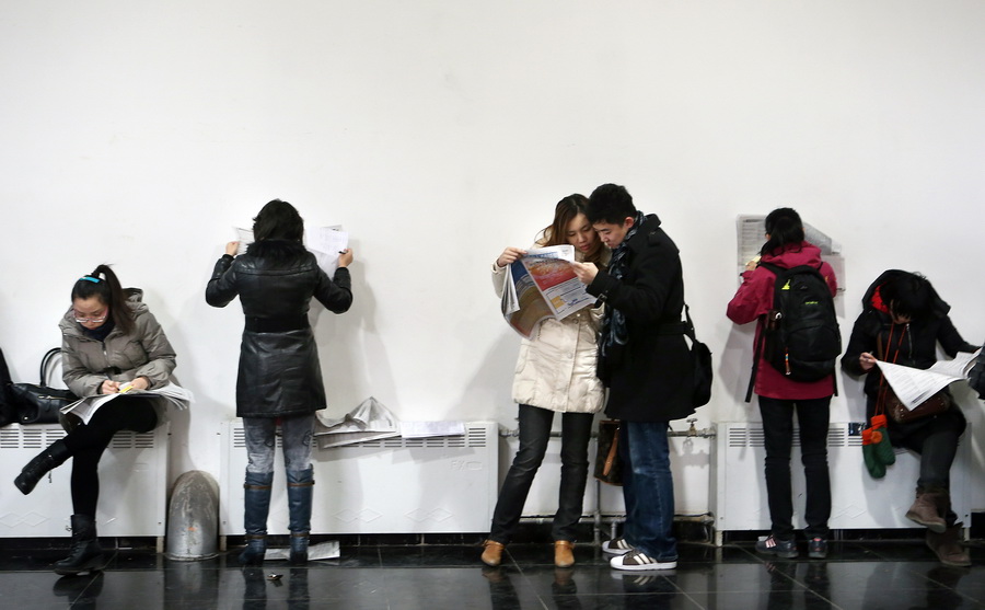 Applicants look at job information in a job fair for postgraduates in Beijing on Jan. 6, 2013. The job fair provided 18,000 job opportunities to the graduates. (Xinhua/Wan Xiang)
