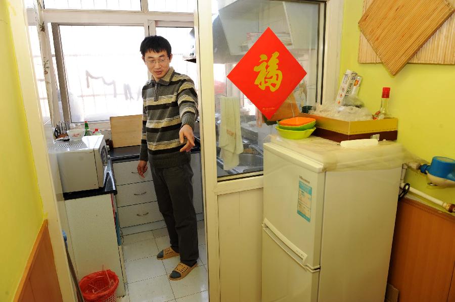 Xu Pengfei, China's first individual user of grid-connected photovoltaic (PV) power, points to the appliances in his flat which uses PV power, in Qingdao, east China's Shandong Province, Jan. 13, 2013. As Xu's "personal power plant", the eight pieces of PV solar batteries have a total installed capacity of 2 kW, with a grid-connected voltage of 220 V. It not only provides electricity for Xu's family, but also sells surplus electricity to the state grid, which has been the first successful case ever in China. (Xinhua/Li Ziheng) 