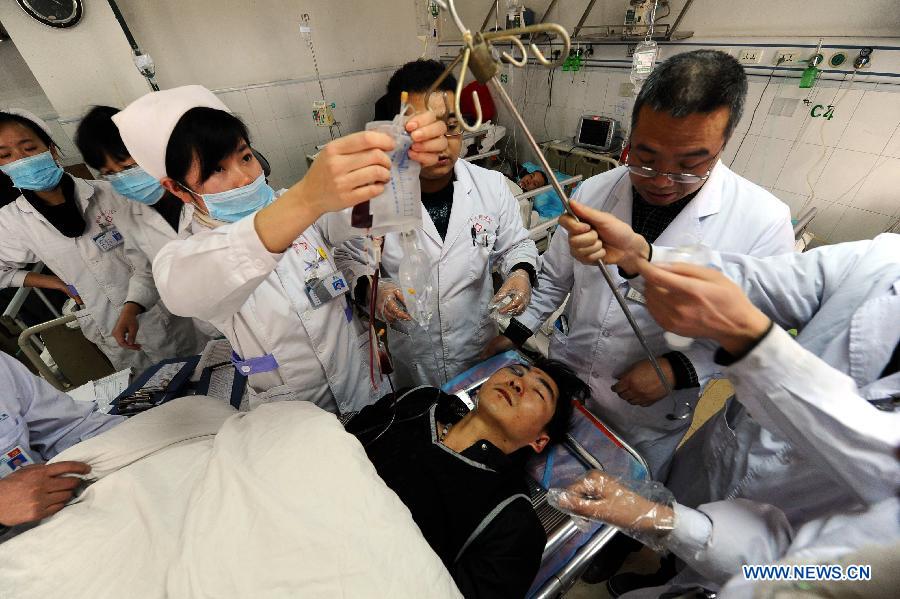 Doctors give emergency treatment to a man injured in an accident on an express way in Xifeng county, southwest China's Guizhou Province, Jan. 13, 2013. Five people died and 19 others were injured after a coach collided with a guardrail and rolled over around 5 a.m. Sunday. (Xinhua) 