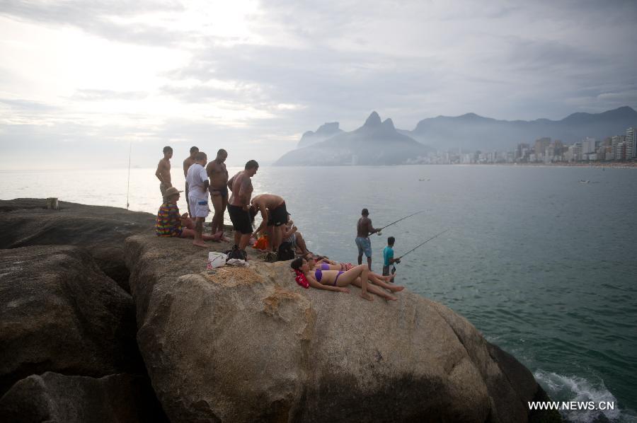 People have a rest on a rock in Arpoador in Rio de Janeiro, Brazil, Jan. 13, 2013.(Xinhua/Weng Xinyang)