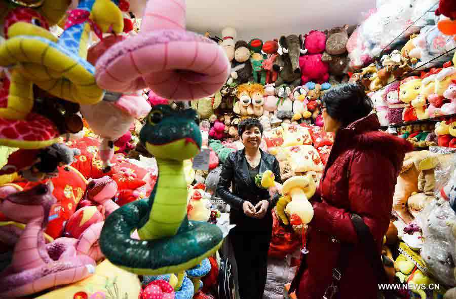 A saleswoman introduces a cartoon figure of snake at Tianyi small commodities market in Beijing, capital of China. Jan. 13, 2013. The coming lunar new year, which falls on Feb. 10, 2013, marks the Year of Snake on the Chinese Zodiac.(Xinhua/Zheng Yong)