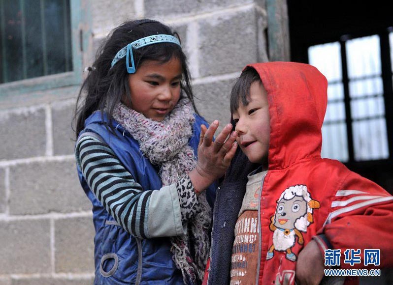 Li Azuo wipes her naughty young brother’s running nose in village of Guangxi on Jan. 8, 2013. (Xinhua/Zhou Hua)