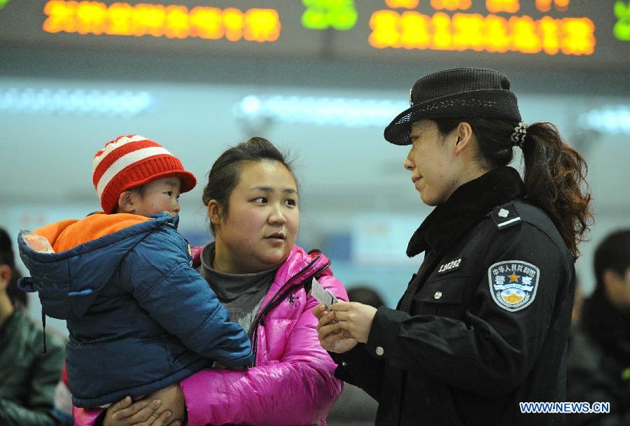 A policewoman helps passengers with buying tickets in a railway station in Chengdu, capital of southwest China's Sichuan Province, Jan. 14, 2013. The peak of Spring Festival travel train tickets purchase started from Jan. 13, 2013 in Chengdu.(Xinhua/Xue Yubin)