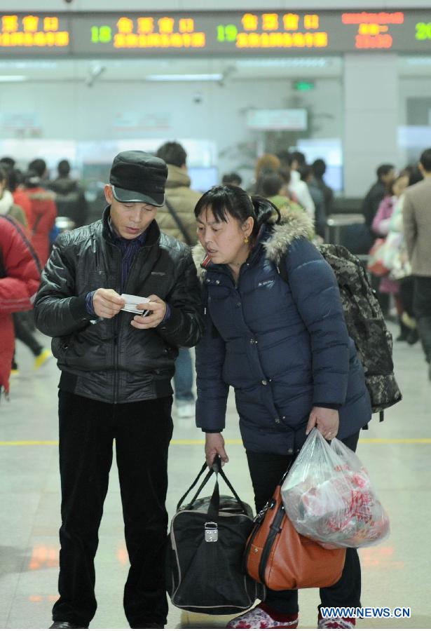 A couple look at their tickets in a railway station in Chengdu, capital of southwest China's Sichuan Province, Jan. 14, 2013. The peak of Spring Festival travel train tickets purchase started from Jan. 13, 2013 in Chengdu. (Xinhua/Xue Yubin) 