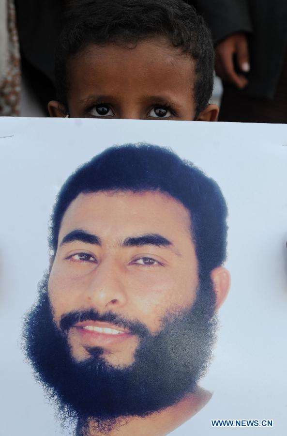 A family member of a Yemeni prisoner in Guantanamo displays a picture of him during a rally demanding the release of prisoners held in Guantanamo, in front of the Yemeni President's Palace, in Sanaa, Yemen, Jan. 14, 2013. (Xinhua/Mohammed Mohammed)
