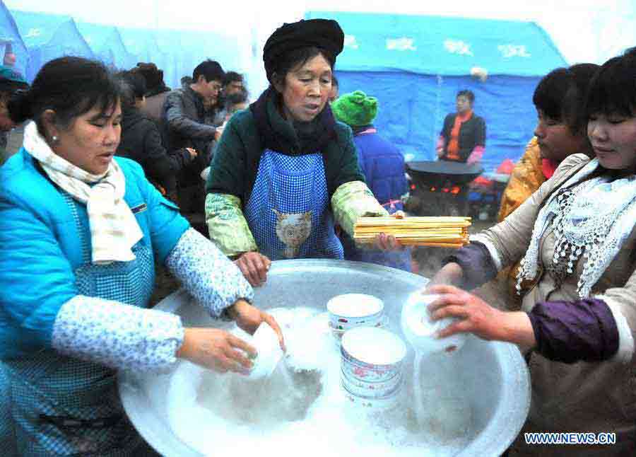 Volunteers from other villages wash dishes in the makeshift tents in Zhenxiong County of Zhaotong City, southwest China's Yunnan Province, Jan. 14, 2013. Forty-six people died and two others injured in a landslide which hit the Zhaojiagou area of Gaopo Village around 8:20 a.m. on Jan. 11. More than 500 villagers have been moved to makeshift tents near the village. (Xinhua/Chen Haining) 