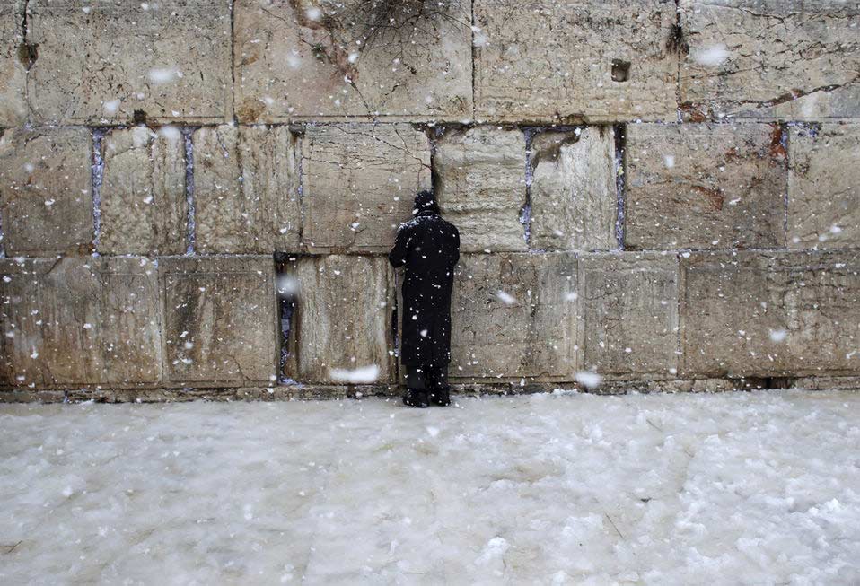 Snow falls as a Jewish man prays at the Western Wall in Jerusalem's Old City, Thursday, Jan. 10, 2013. Stormy weather conditions continued on Thursday with snow, torrential rains and strong winds across the region. (Xinhua/Reuters)
