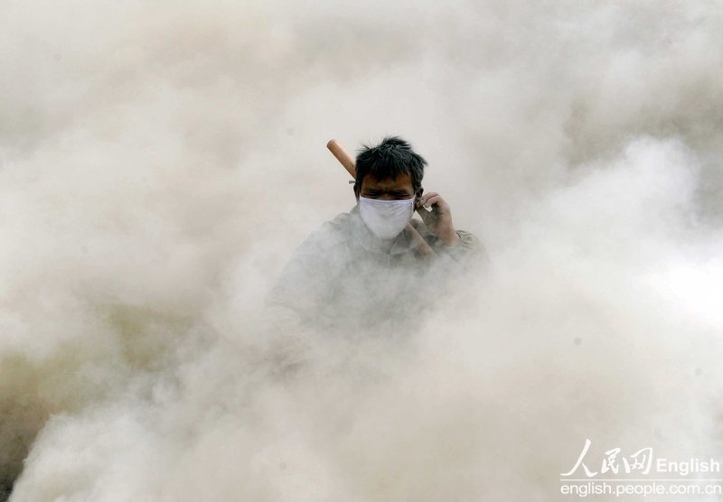 A worker is surrounded by dust storm and cannot open eyes after a forklift truck driving past him on Sept. 14, 2012. (Photo/People's Daily Online)