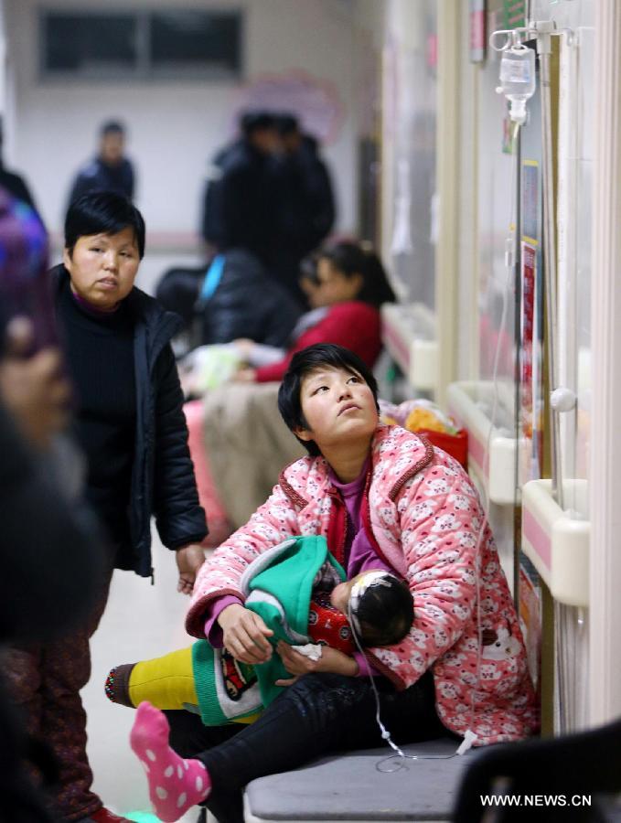 A mother carries her child in the arm as the child receives transfusion treatment on a corridor of Huaibei People's Hospital in Huaibei, east China's Anhui Province, Jan. 14, 2013. Continuous foggy condition in many Chinese cities these days has caused more children to get sick. (Xinhua/Wan Shanchao)  