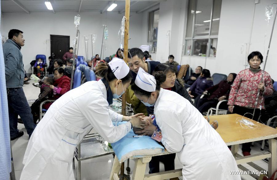 Two nurses try to give a child an acupuncture treatment in Jinhu Traditional Chinese Medicine Hospital in Jinhu County, east China's Jiangsu Province, Jan. 15, 2013. Continuous foggy condition in many Chinese cities these days has caused more children to get sick. (Xinhua/Chen Yibao) 