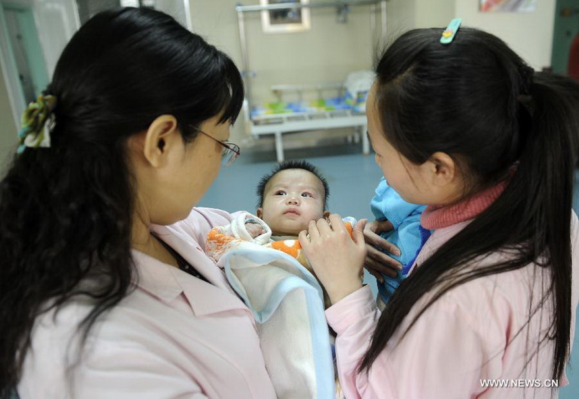 Two teachers take care of a newly-born baby in Ningxia Children Welfare Center in Yinchuan, capital of northwest China's Ningxia Hui Autonomous Region, Jan. 15, 2013. The welfare center recently moved to a new home, providing a more comfortable living environment to more than 300 orphans. (Xinhua/Li Ran) 