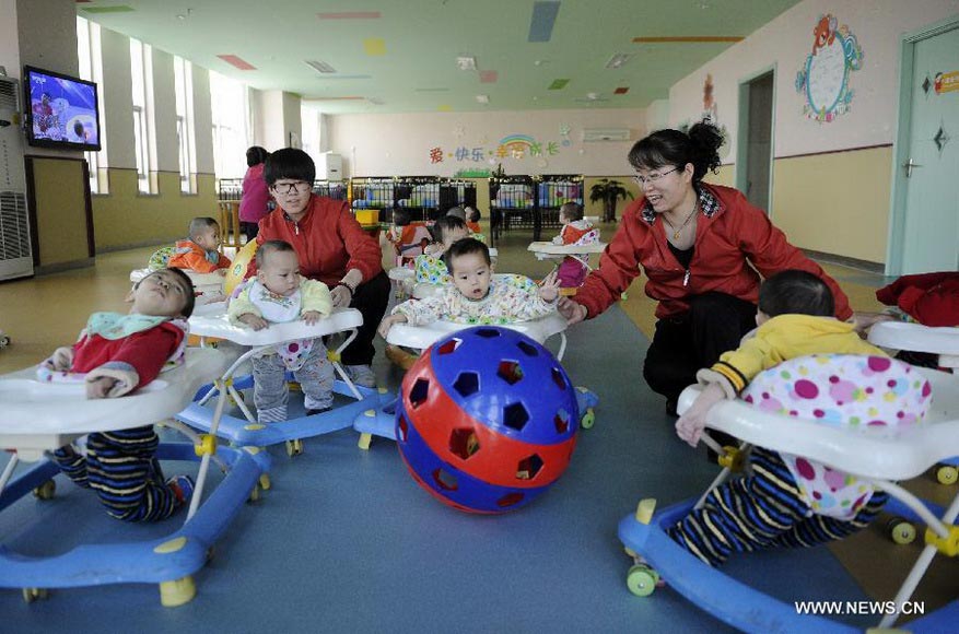 Teachers take care of children in Ningxia Children Welfare Center in Yinchuan, capital of northwest China's Ningxia Hui Autonomous Region, Jan. 15, 2013. The welfare center recently moved to a new home, providing a more comfortable living environment to more than 300 orphans. (Xinhua/Li Ran)  