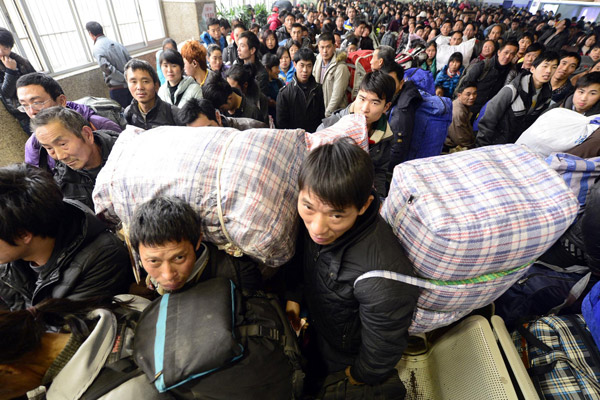 Two migrant workers, originally from Chongqing, Southwest China, carry big bags on their backs while waiting to board a homebound train at Hangzhou railway station in East China's Zhejiang province, on Jan 15, 2013. Hangzhou railway station is expected to transport around 34 million people during the approaching Spring Festival travel rush, which is still more than 10 days away. (Photo/Xinhua)