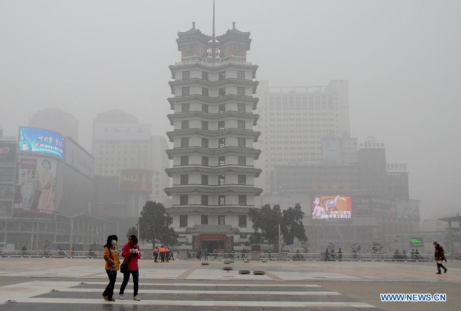 People walk past the "Feb. 7 Memorial Tower" which is shrouded by the fog in Zhengzhou, capital of central China's Henan Province, Jan. 16, 2013. Affected by a cold front, the haze which has lingered in most parts of Henan for the past two weeks will begin to disperse on Jan. 17, according to the meteorological authority. (Xinhua/Wang Song)