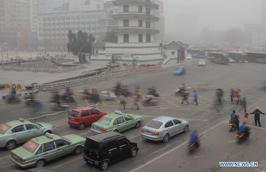 Pedestrians walk across a street in Zhengzhou, capital of central China's Henan Province, Jan. 16, 2013. Affected by a cold front, the haze which has lingered in most parts of Henan for the past two weeks will begin to disperse on Jan. 17, according to the meteorological authority. (Xinhua/Wang Song)