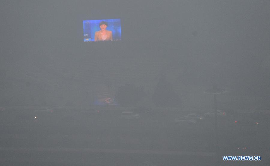 An outdoor screen glimmers as heavy fog shrouds Zhengzhou City, capital of central China's Henan Province, Jan. 16, 2013. The fog and smog has lingered in Zhengzhou for a few days, affecting local traffic and residents' daily life. (Xinhua/Zhu Xiang)