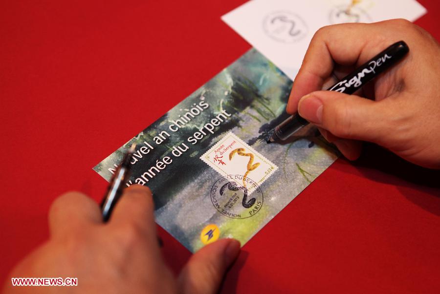 Chinese artist in France Li Zhongyao autographs on the commemorative stamps for China's upcoming lunar new year, Year of the Snake, at a post office in Paris, capital of France, Jan. 4, 2013. The French postal department began to sell on Friday the commemorative stamp for China's Year of the Snake which is due to begin on Feb. 10, 2013. (Xinhua/Gao Jing)