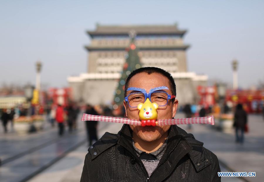 A tourist wears a cartoon mask to pose for photo on the Qianmen Street in Beijing, capital of China, Jan. 16, 2013. Beijingers on Wednesday saw their first sunshine in seven days, with a cold front dispersing the lingering smog in the city. (Xinhua/Li Fangyu)