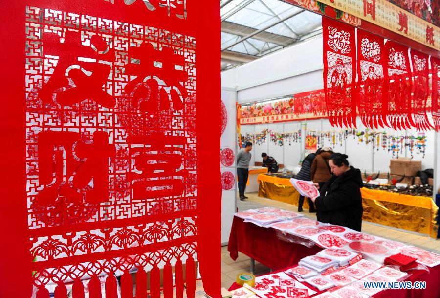 Visitors select paper-cut artworks during the 4th Jilin Agricultural Expo for Winter in Changchun, capital of northeast China's Jilin Province, Jan. 16, 2013. Many people came to purchase goods for the coming Spring Festival. (Xinhua/Xu Chang)