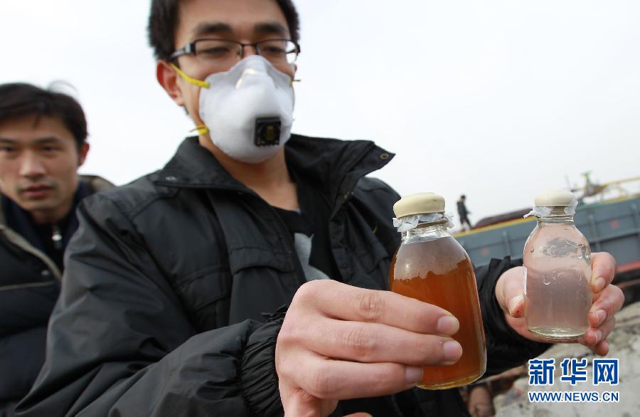 A worker from Shanghai environmental protection department shows leakage samples (left) and water samples collected on the chemical leakage site on Jan. 11, 2013. (Xinhua/Pei Xin)