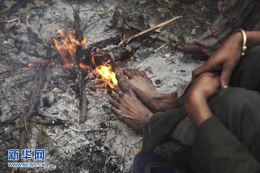 A homeless man warms his feet over a fire on a street on a cold winter morning in Indian-controlled Kashmir on Jan. 8, 2013. (Xinhua/AP)