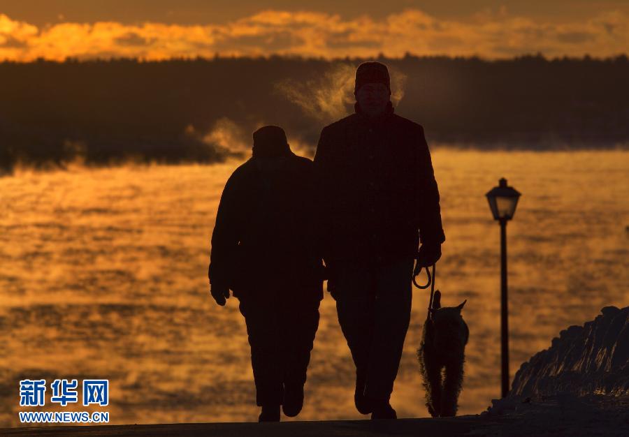 A couple goes for a walk with their dog on the walkway in Portland, Maine on Jan. 3, 2013. From last December to January, the world has undergone a host of unprecedented extreme weathers. Once again global climate change rings the alarm, questioning the way of development of human being. (Xinhua/AFP)