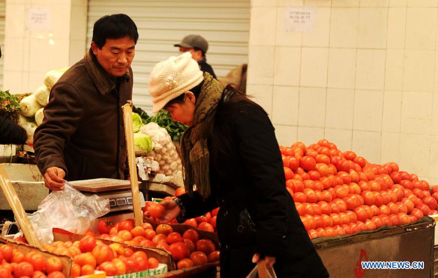 A local resident selects tomatoes at a market on Tabei Road in Shijiazhuang, capital of north China's Hebei Province, Jan. 16, 2013. According to the Ministry of Commerce, the price of agricultural products in 36 large-and-medium-sized cities across the nation continued to rise from Jan. 7, 2013 to Jan. 13, 2013, a continuous rising in 11 consecutive weeks. (Xinhua/Zhu Xudong)