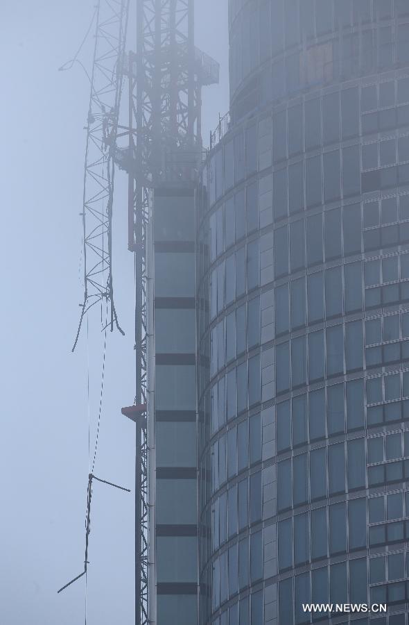 Photo taken on Jan. 16, 2013 shows the damaged crane and the apartment block in the fog at the construction site of the apartment block in central London, Britain. Two people were killed and another two were injured after a helicopter crashed into a construction crane near Wandsworth Road, south of River Thames in central London earlier on Wednesday. (Xinhua/Yin Gang)