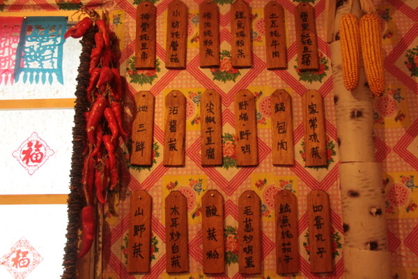 This photo on December 20, 2012, shows local dishes written on a wooden board in a house made of snow, which contains a collection of local rural furniture, daily articles and hunting products in Harbin, northeast China's Heilongjiang Province. (CRIENGLISH.com)