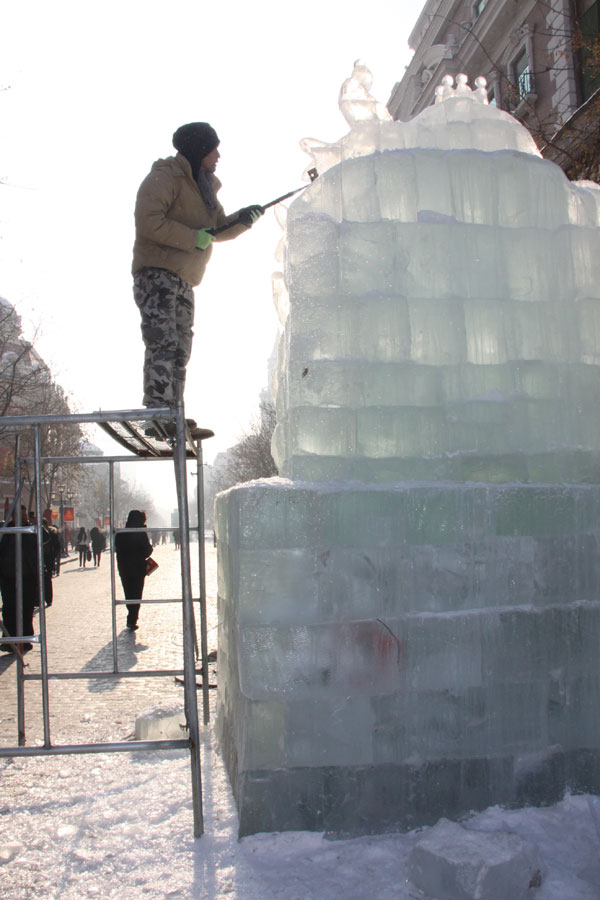 An ice sculptor carves a block of ice on Central Street in Harbin, northeast China's Heilongjiang Province, on December 18, 2012. (CRIENGLISH.com)