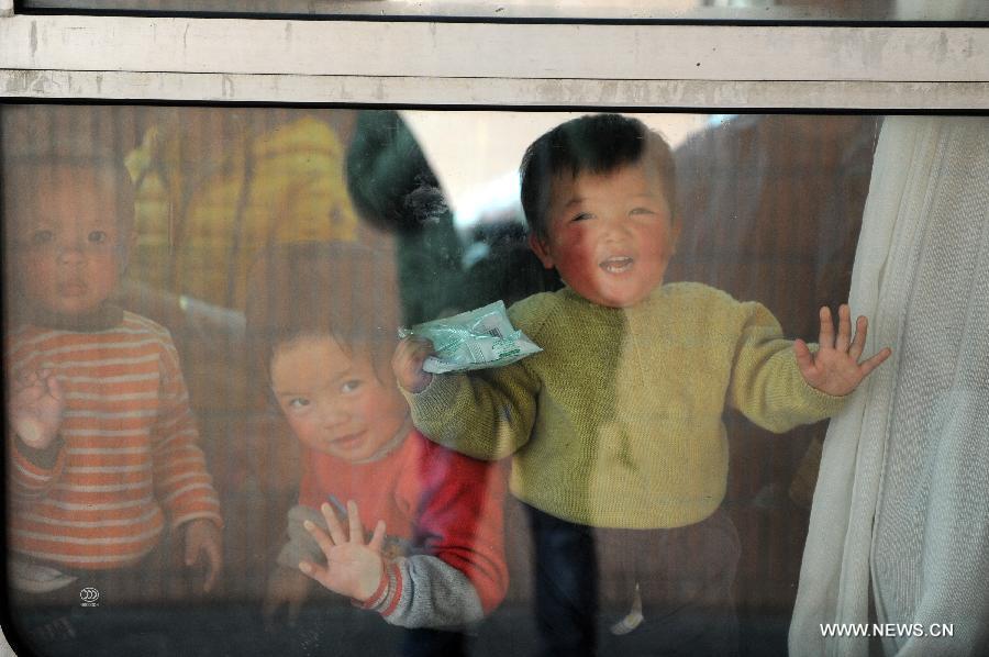 Children look out of the window on the train at the Hangzhou Railway Station in Hangzhou, east China's Zhejiang Province, Jan. 17, 2013. Some migrant workers have started to return home in order to avoid the Spring Festival travel peak that begins on Jan. 26 and will last for about 40 days. The Spring Festival, the most important occasion for a family reunion for the Chinese people, falls on the first day of the first month of the traditional Chinese lunar calendar, or Feb. 10 this year. (Xinhua/Ju Huanzong) 