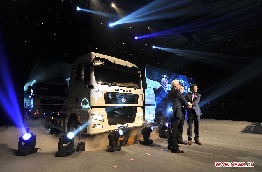 Guests pose for photos in front of the first SITRAK duty truck during the off assembly line ceremony at the China National Heavy Duty Truck Group (CNHTC) Jinan Commercial Vehicle Co. Ltd, in Jinan, capital of east China's Shandong Province, Jan. 17, 2013. As advanced heavy duty truck produced by CNHTC in cooperation with MAN Truck & Bus AG from Germany (MAN), the SITRAK duty truck was off assembly line on Thursday. (Xinhua/Xu Suhui)