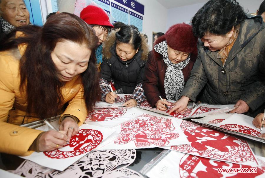 People write down their new year wishes on paper-cut artworks in the Changhong Road Resident's Committee in Xiangyang City, central China's Hubei Province, Jan. 17, 2013. The committee held a paper-cut activity to welcome the coming Spring Festival. (Xinhua/Gong Bo) 