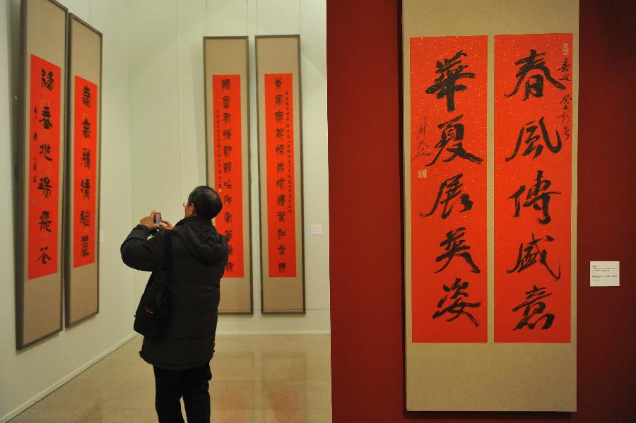 A citizen takes photos of couplet calligraphy works at the "Calligraphy Inheriting--New Year Couplet Calligraphy Exhibition" at the National Art Museum of China in Beijing, capital of China, Jan. 18, 2013. The exhibition kicked off on Friday, displaying over a hundred couplet works.(Xinhua/Lu Peng) 